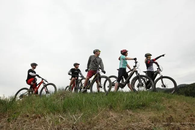 Detail from the Witch cycling trail - A group of cyclists on a gravel road climbing up Slivnica, looking towards the summit.
