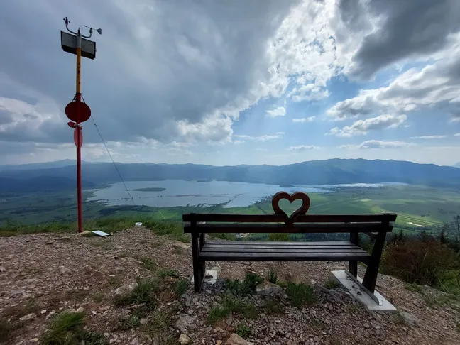 Detail from the Bear cycling trail - a view of Lake Cerknica from the bench of love on Slivnica in cloudy weather. Wooden bench with a heart-shaped cutout at Slivnica viewpoint.