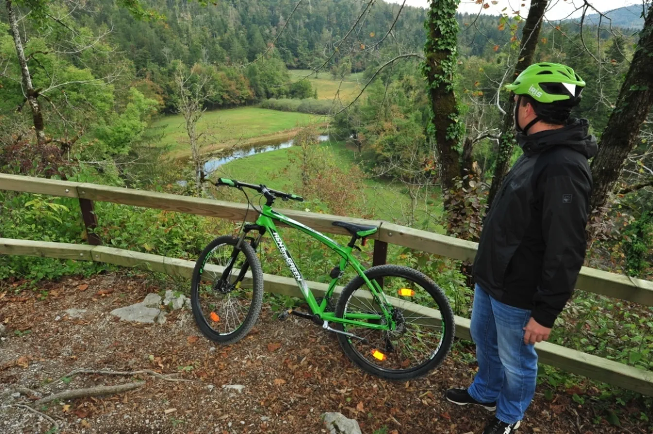 Kolesar občuduje razgled na dolino reke Rak z Velikega naravnega mostu