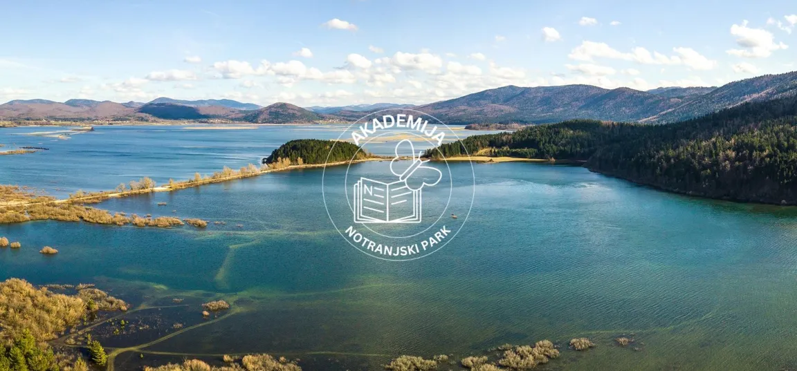 Pogled iz zraka na Cerkniško jezero z logotipom Akademije Notranjski park.