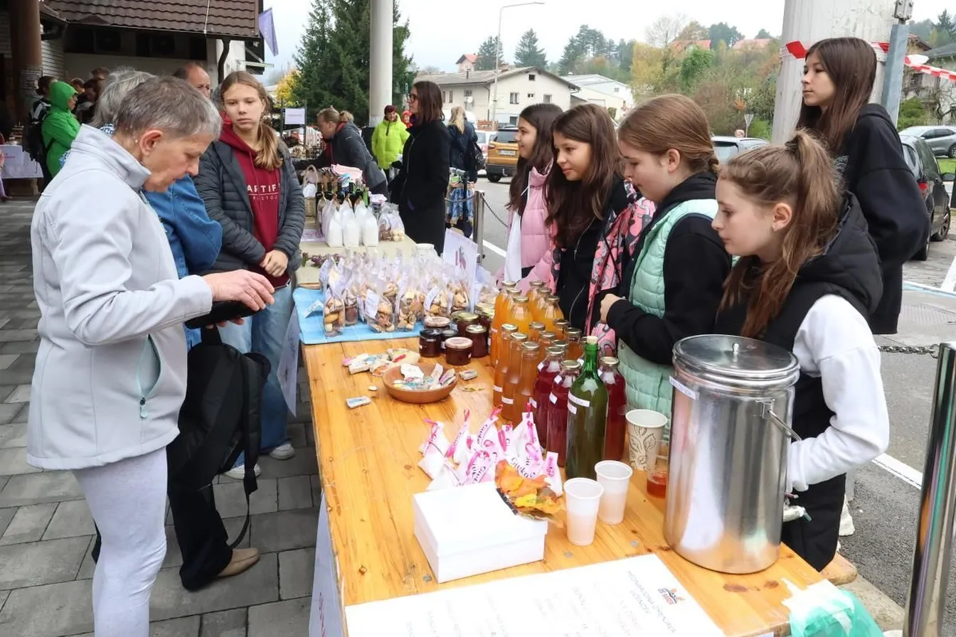 Visitors to the autumn fair in Rakek stand at a table with fruit juices in bottles and dried fruit.