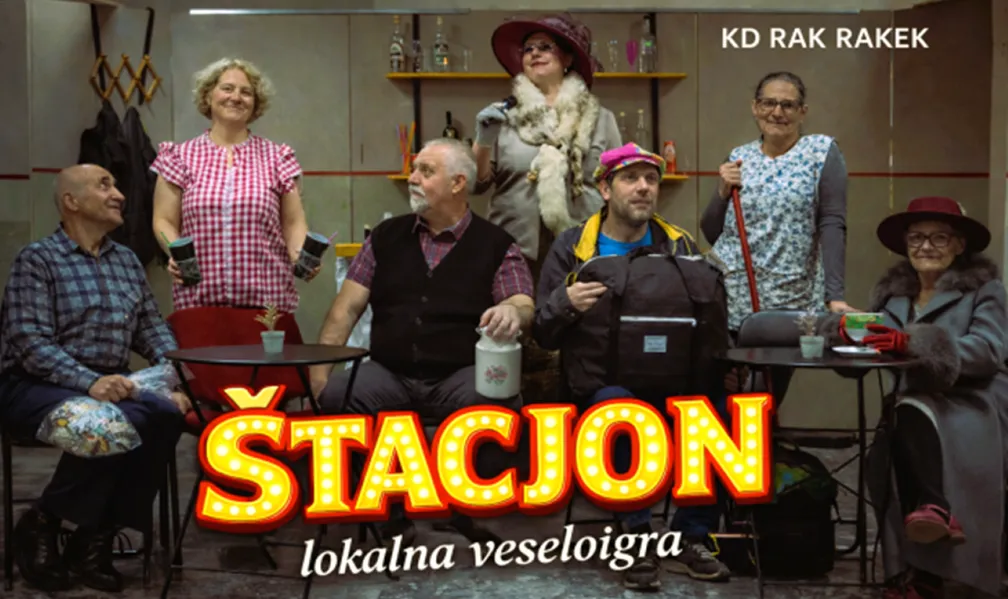 A group of six actors of different generations pose on stage in a scene from the local comedy play “Štacjon.” They wear colorful character costumes – from aprons and hats to an elegant coat with a fur collar – while sitting and standing around small tables in a setting resembling a village café or waiting room. The poster features the large illuminated title “ŠTACJON” with the subtitle “local comedy play,” and the text “KD Rak Rakek” in the upper right corner.
