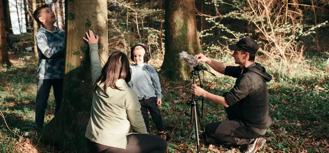 A child listens to recorded nature sounds during an audio experience in the forest of Notranjska Park.
