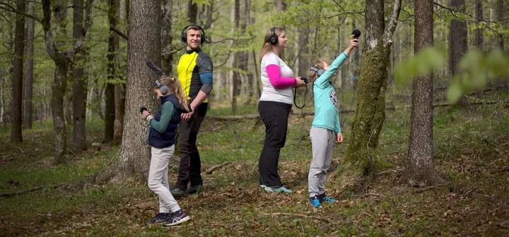 Družina raziskuje in snema zvoke narave med zvočnim sprehodom v Notranjskem parku.