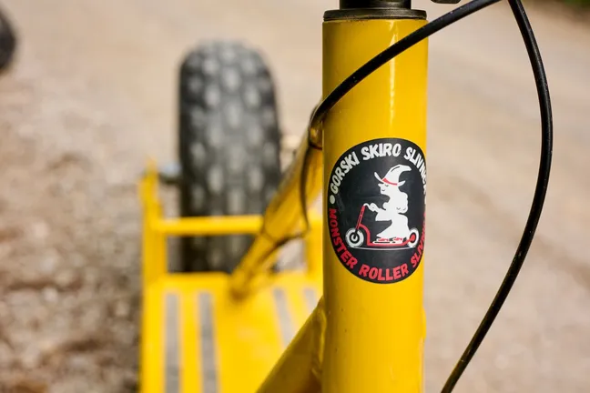 Detajl rumenega gorskega skiroja z logotipom - stilizirano coprnico.