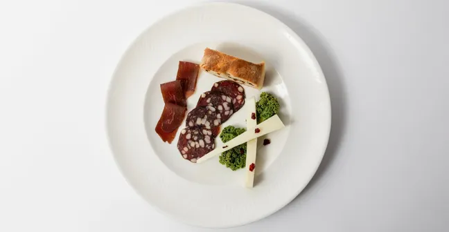 Local cured meats, cheese and bread served on a plate.