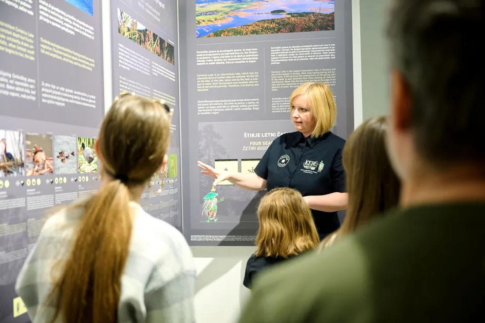 A guide in the ornithology classroom by Lake Cerknica provides information to visitors next to information boards.