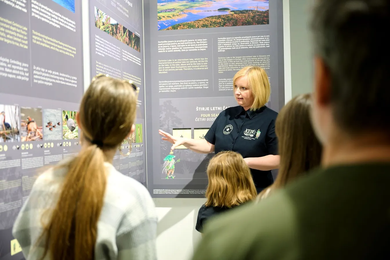 A guide in the ornithology classroom by Lake Cerknica provides information to visitors next to information boards.