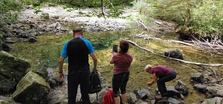 Pohodniki se ovežujejo pri potočku.