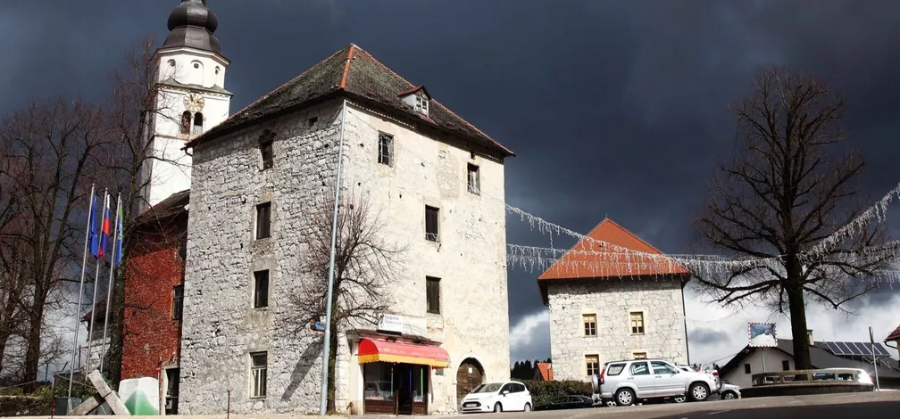Stolpa protiturškega tabora v Cerknici s cerkvijo v ozadju.