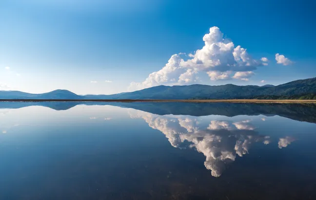 Lake Cerknica with clouds reflecting on the water surface.
