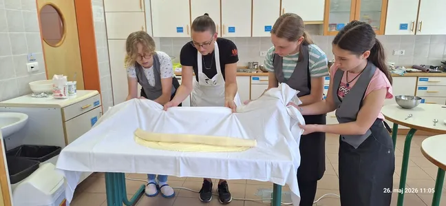 Udeleženke kuharske delavnice raztezajo testo za pripravo domačih skutnih štrukljev.