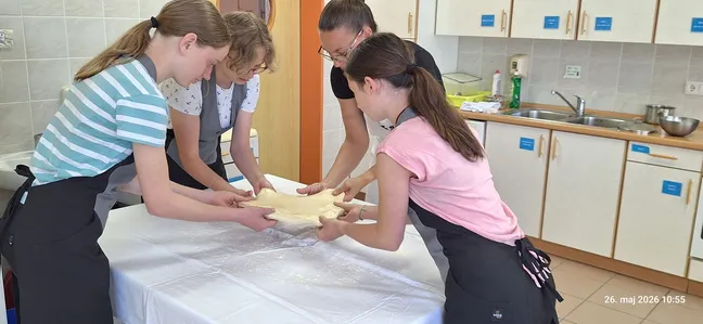 Skupina udeleženk skupaj pripravlja in oblikuje testo za notranjske skutne štruklje.