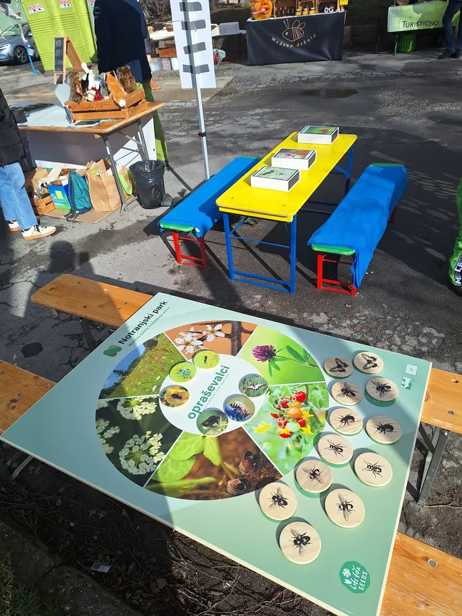 Promocijska stojnica z izobraževalnimi materiali o opraševalcih, interaktivnimi pripomočki in informativnimi vsebinami.