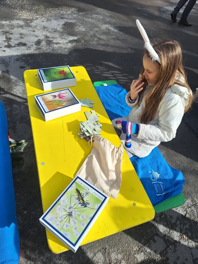 Deklica sedi za mizo in rešuje sestavljanko z motivi rastlin kot del izobraževalne aktivnosti.