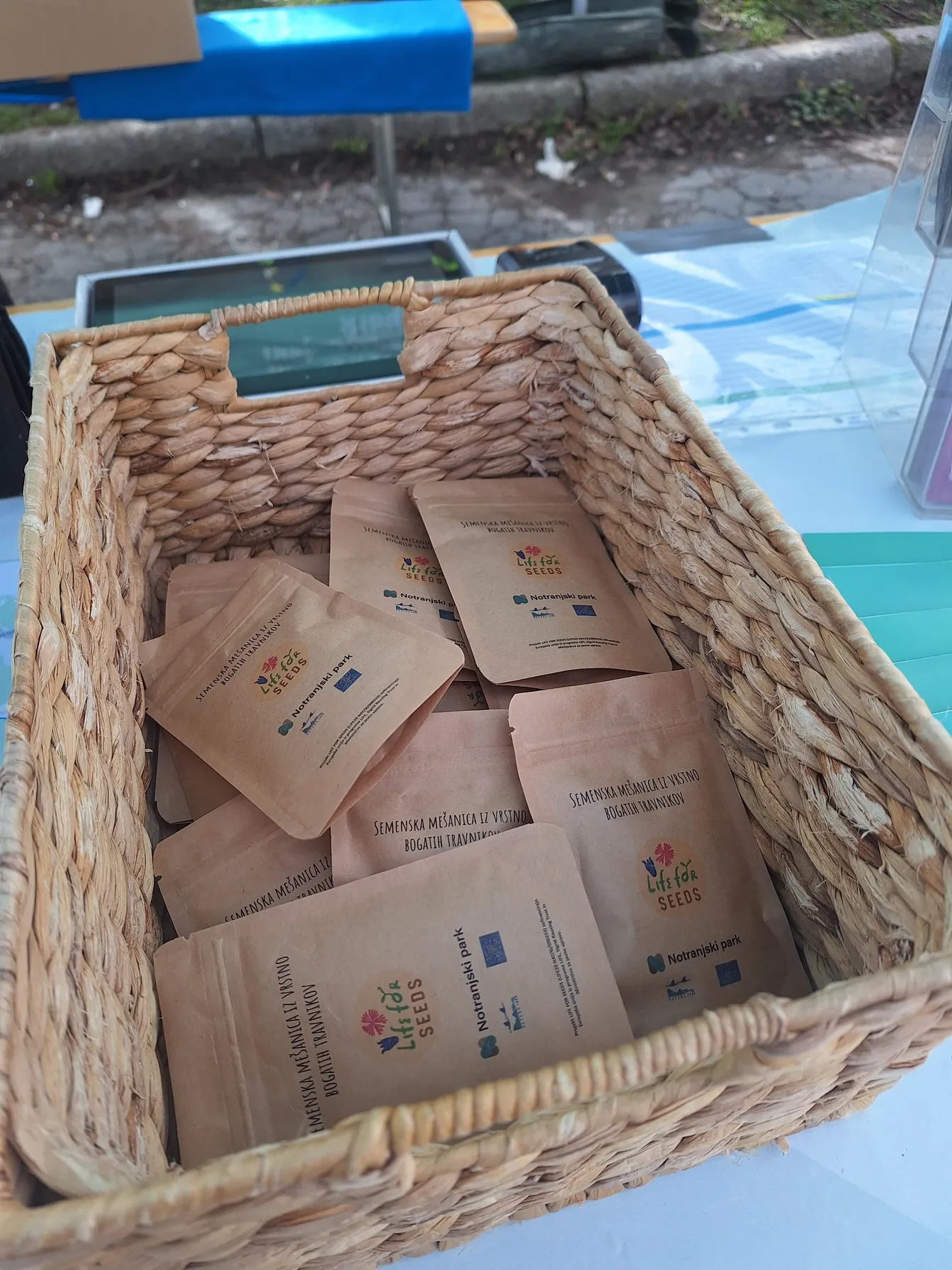 Košara z vrečkami semen travniških rastlin projekta LIFE FOR SEEDS, pripravljenimi za razdeljevanje obiskovalcem.