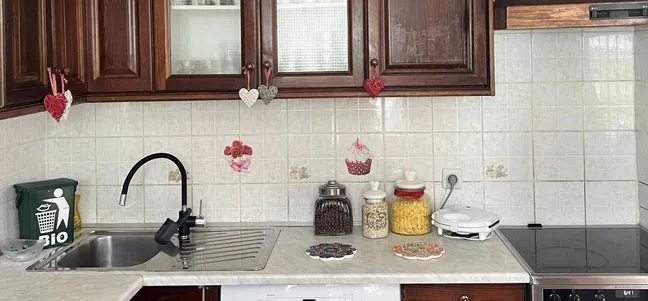 Green Garden Home-Urejena kuhinja z lesenimi omaricami, srčkastimi okraski, lončki s sestavinami in električnim štedilnikom.