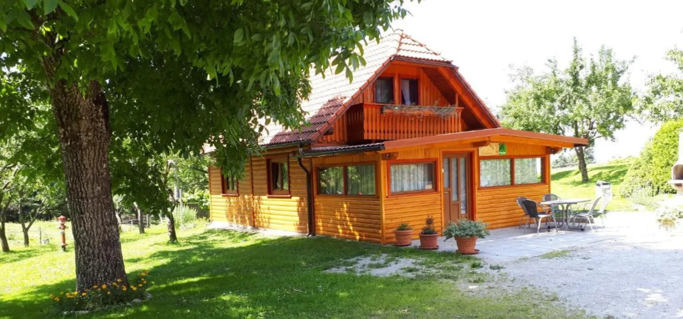 Žnidarjevi Farm-A picturesque wooden cottage surrounded by lush greenery, featuring a well-maintained garden and outdoor seating area.