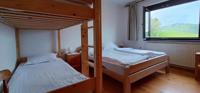 Bedroom with a double bed and bunk bed with a view of nature at Tourist farm Strle.