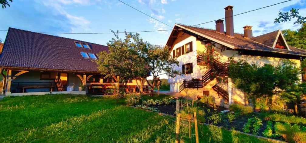Zunanji pogled na hišo in gospodarsko poslopje z vrtom v nastanitvi Turistična kmetija Strle.