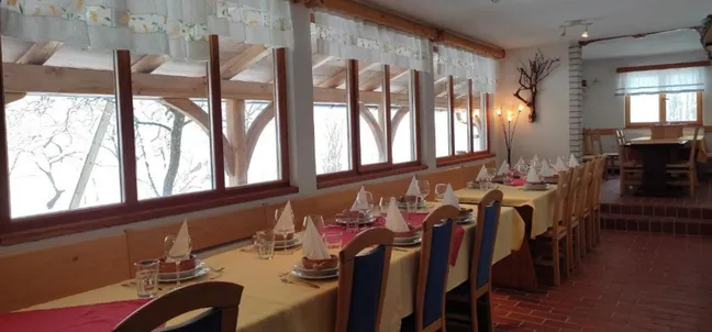 Dining room with long tables set with tablecloths and decorations at Tourist farm Strle.