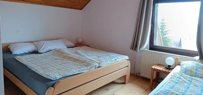 Bedroom with a double bed, a single bed, and wooden furniture at Tourist farm Strle.
