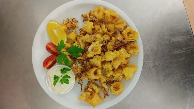 Ocvrti kalamari s tatarsko omako, rezino limone in paradižnika.