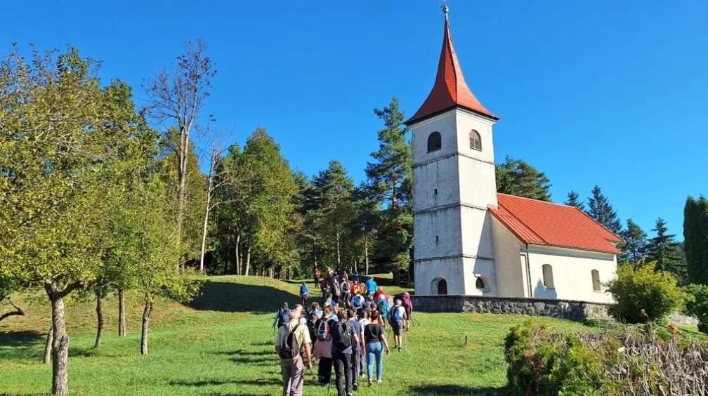Pohodniki hodijo proti cerkvici v vasi SElšček.