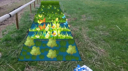 A meadow with a wooden fence on the left side. In the center of the image are rectangular inserts showing different stages of plant growth – from small seedlings to fully developed plants with flowers and butterflies.